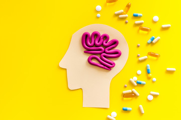 Treat brain diseases. Head with plastiline meanders and pills on yellow background top view space for text