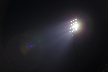 Sport light in football stadium on night time with a lot of little insects.