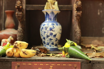 various Buddhist food offerings on a shelf before and alter in an ancient temple in Northern Thailand, Southeast Asia