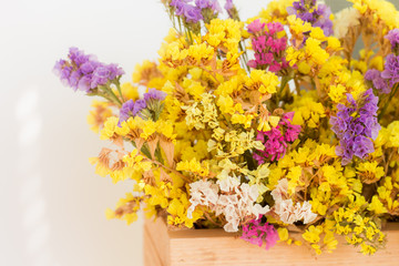 bouquet of autumn colorful bright dried flowers (limonium, Sea lavender) in a wooden box on a white background, close up, copy space