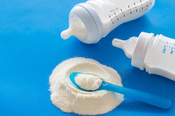 Powdered food for newborn baby near baby bottle on blue background space for text