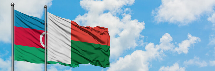 Obraz premium Azerbaijan and Madagascar flag waving in the wind against white cloudy blue sky together. Diplomacy concept, international relations.