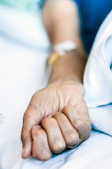 Hand of patient in serious condition is given a medicine through a dropper (healthcare background with an intravenous system).