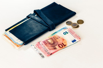 Close up money euro banknotes in blue purse and coins on white background.