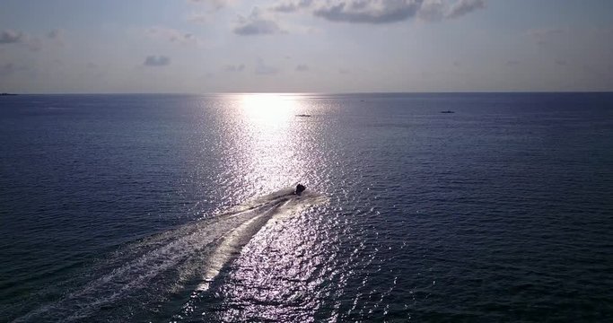 Sunset over water in Malaysia, boat sailing towards the sun in open waters