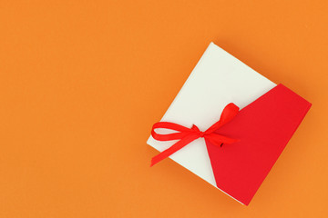 Red and beige gift box on a bright orange background. Flat lay top view copy space