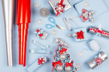 Christmas background - gift boxes in red, blue and silver metallic color with ribbons, decorations, scissors, wrapping paper, straws as pattern, top view.