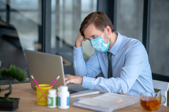 Office worker wearing protective mask after catching cold