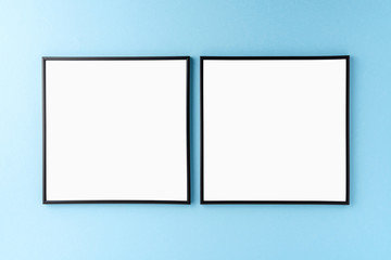 Two black photo frames with copyspace on blue background. Home decoration