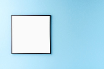 Empty photo frame hanging on blue wall. Mockup