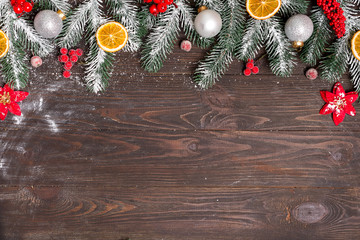 Obraz na płótnie Canvas Christmas greeting card with decor and fir tree branch on a dark wooden background. Top view with copy space for your greetings