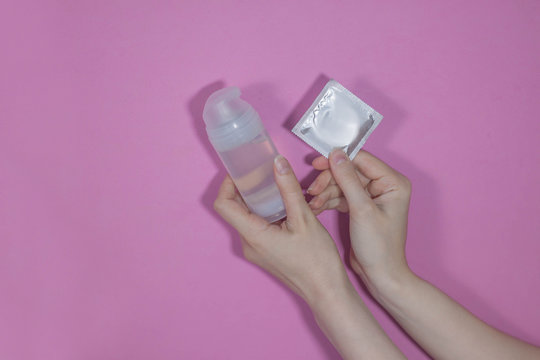 Intimate lubrication and condom in hands on a colored background. Comfortable sex, protected sex.