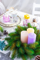 Place table setting for Christmas white table with purple decor elements and green wreath Christmas tree