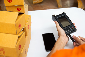 delivery staff man is using the card machine to pay the goods before packing in the box to deliver...