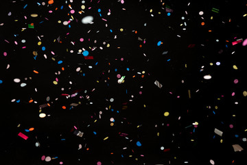 colorful party confetti flying in front of black