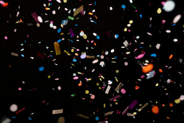 colorful party confetti flying in front of black - obrazy, fototapety, plakaty