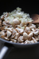 сooking onions and mushrooms on wok pan