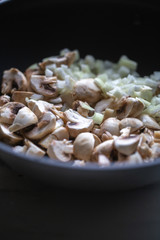 сooking onions and mushrooms on wok pan