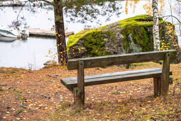 Bench in the autumn park on the shore, Water and a motor boat.