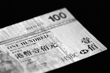 One hundred Hong Kong dollars banknote on a dark background close up. Black and white