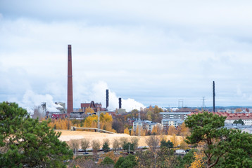 Fototapeta na wymiar Cityscape, red brick buildings of an old factory, factory chimneys smoke. Ecology problems in Europe.