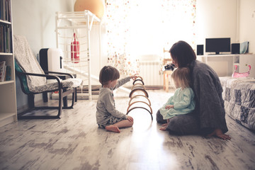 happy mom with two children on the floor in room