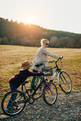 Mother and daughter with bicycles on countryside.