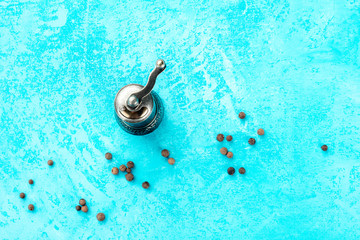 Allspice, Jamaica pepper. Black peppercorns with a vintage pepper mill, overhead shot on a blue...