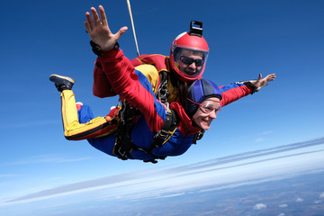 Tandem skydiving. An instructor and his woman-passenger are flying in the sky.