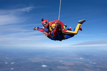 Tandem skydiving. An instructor and his woman-passenger are flying in the sky.