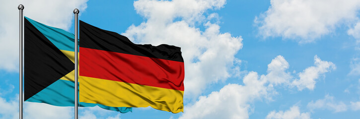 Bahamas and Germany flag waving in the wind against white cloudy blue sky together. Diplomacy concept, international relations.