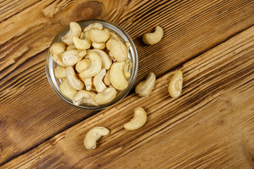 Glass bowl with raw cashew nuts on a wooden table. Top view