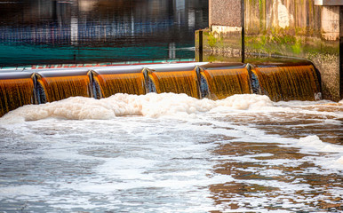 Pollution in the river or canal with foam. Organic scum foaming in the water