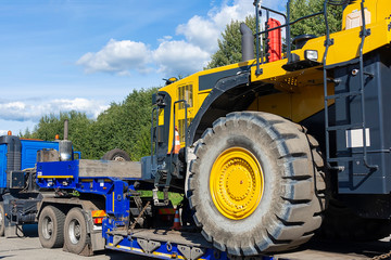 Large truck with a low platform trailer carrying a tractor. A truck for transporting heavy equipment loaded with a large tractor. Highway. Transport