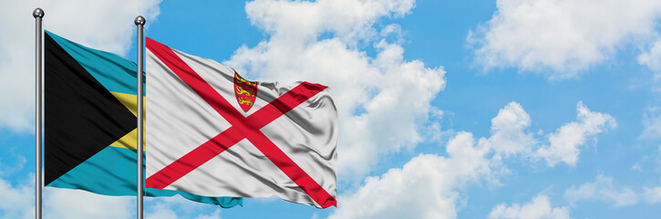 Bahamas and Jersey flag waving in the wind against white cloudy blue sky together. Diplomacy concept, international relations.