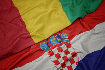 waving colorful flag of croatia and national flag of guinea