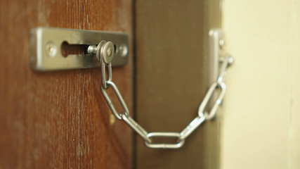 wooden door locked by door latch and chain in vintage style.for security