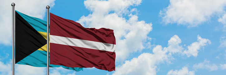 Fototapeta na wymiar Bahamas and Latvia flag waving in the wind against white cloudy blue sky together. Diplomacy concept, international relations.