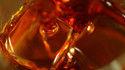 Super macro shot of pouring spirit into glass