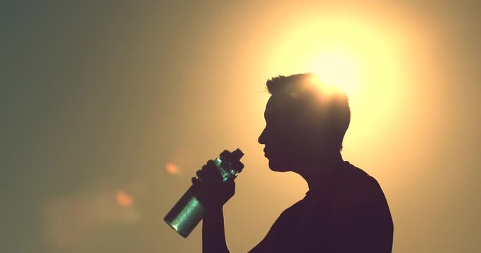 Young man enjoying a drink of water outdoors