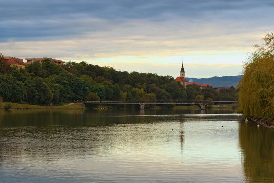 Concept of landscape and nature. Autumn morning view of River Drava during sunrise. Bridge named Studenska brv over river. Maribor, Slovenia