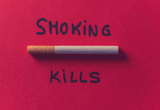 Cigarette isolated on red background with text Smoking kills