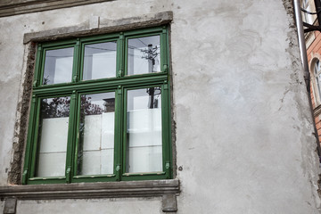 Aged old building facade with green window. Historical city elements. European architecture