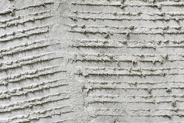 Rough grooved gray textured cement wall with pattern prepared for laying tile. Closeup