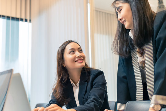 Picture close up cute of two business asian woman working and using computer in office, asisn woman sitting together looking at laptop screen in office