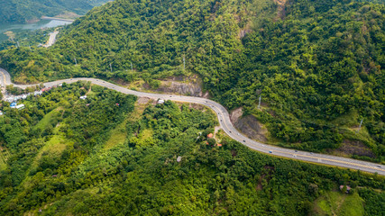 Picture aerial view of curve road from above, road with cars through green forest and mountain landscape of rural Thailand at northern region