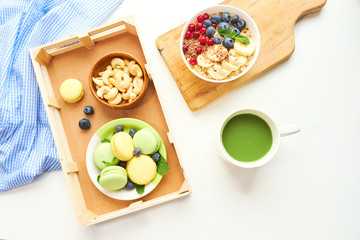 matcha green tea, breakfast top view white background. oatmeal with berries, toasts on a wooden tray, nuts, coffee