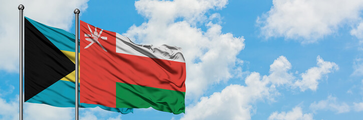 Naklejka premium Bahamas and Oman flag waving in the wind against white cloudy blue sky together. Diplomacy concept, international relations.
