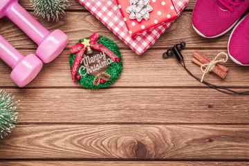 Exercise, Fitness and Working Out Merry Christmas and Happy new year concept, dumbbells, sport shoes, gift boxes with Christmas ornaments decoration on wood background.