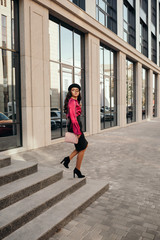 Obraz premium young woman wearing black hat is walking in the streets of City. girl goes down the steps of the business center